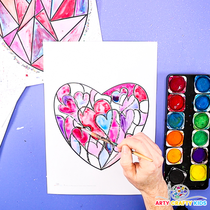 Image of a hand painting the hearts in shades of red, pink and purple.
