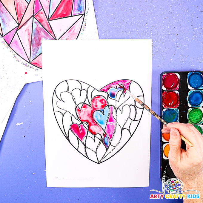 Image of a hand using different watercolor techniques to create heart art.
