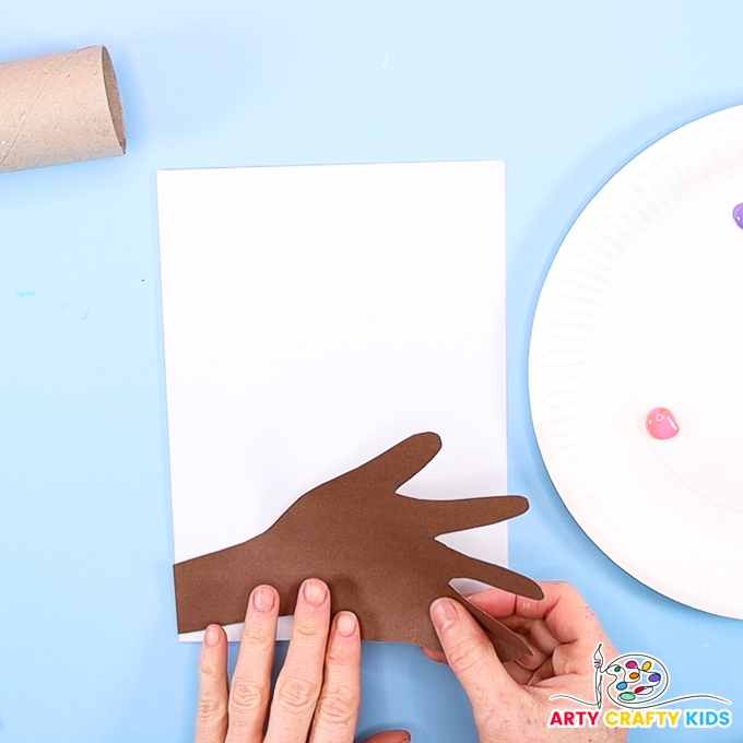 Image of a hand gluing the handprint to the bottom of the Valentine's Day card.