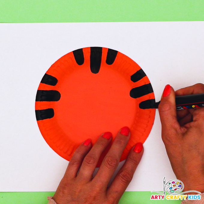 Image features and completing the 3rd set of 3 tiger strips around the parameter of the paper plate.