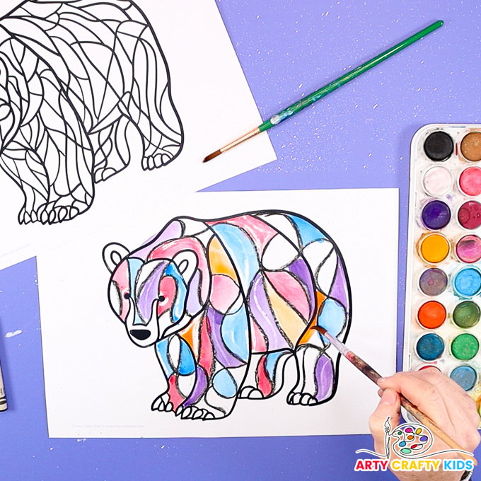 Image of a hand painting the polar bear in lots of different colors using watercolor paint.