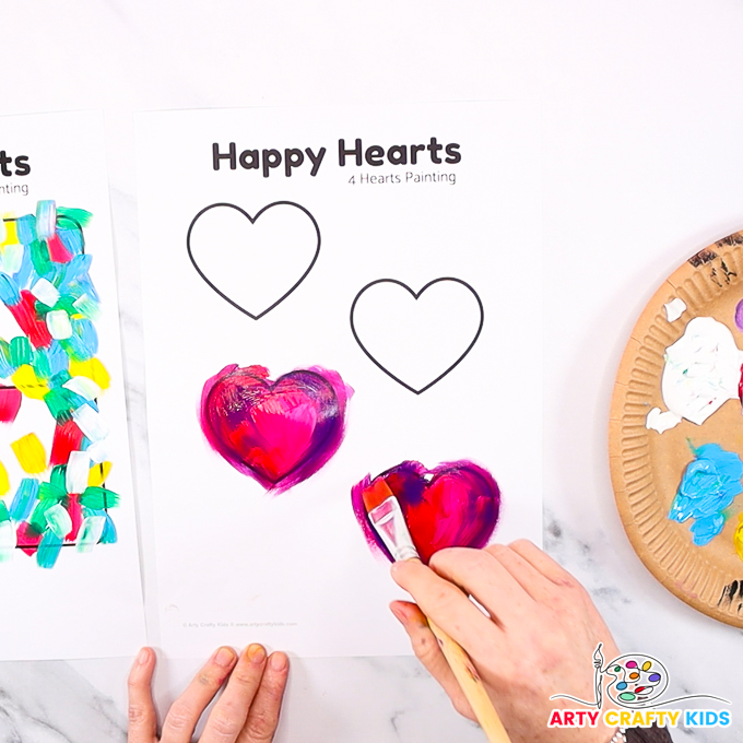 Image feature a hand painting the hearts in a blended red, pink and purple.