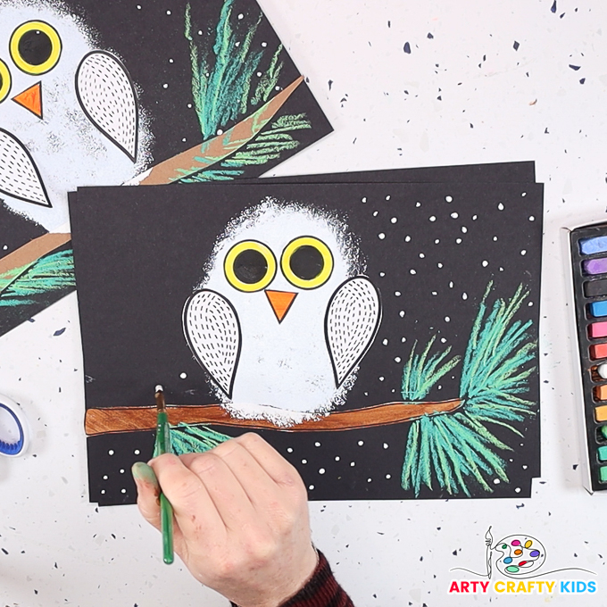Image of a hand painting snowy dots around the sponge painted owl.