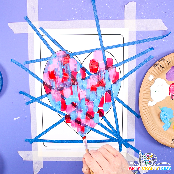 Image of a hand filling the heart templates with red, blue and pink paint strokes.
