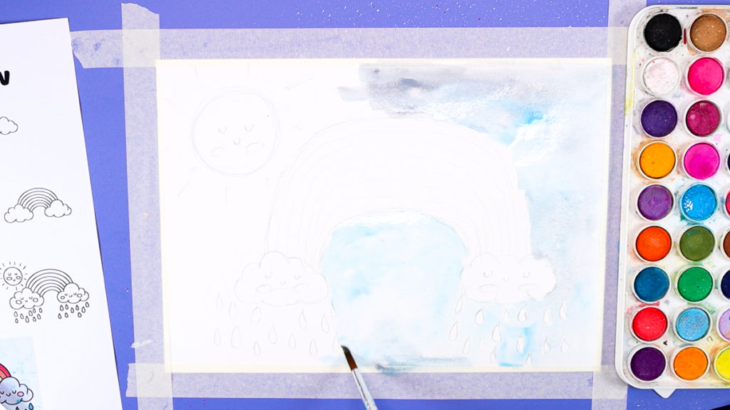 Image of a hand painting the sky blue and gray.