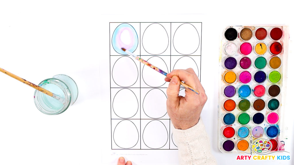 Image of a hand painting the first Kandinsky Easter Egg with watercolor paints.