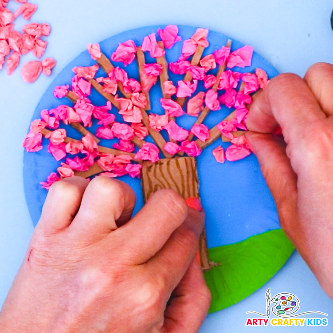 Image of a hand glueing the tissue paper balls to the Spring tree.