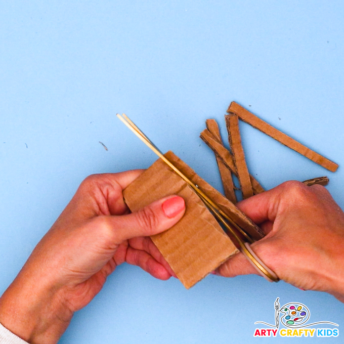 Image of a hand cutting a piece of cardboard into smaller segments.