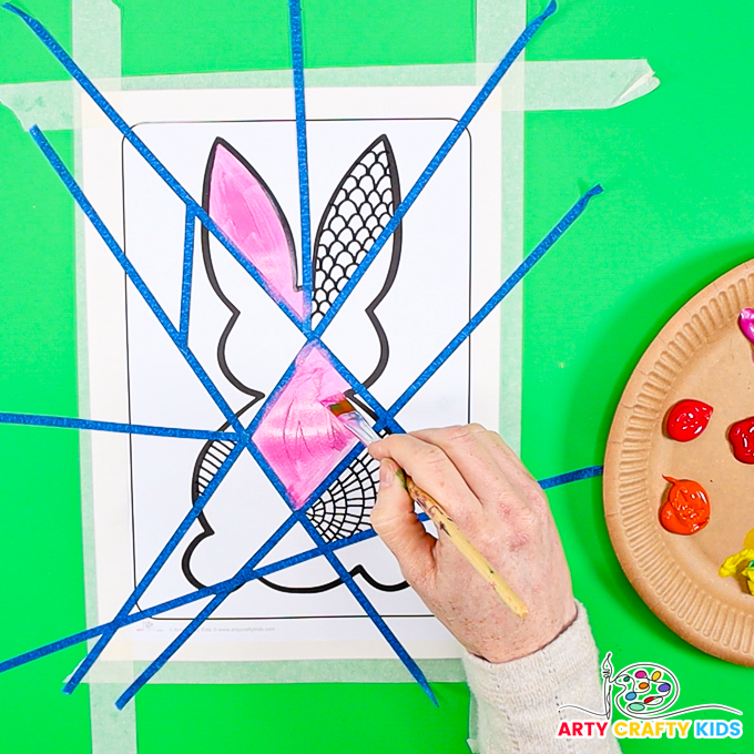 Image featuring a hand painting geometric segments within the bunny template.