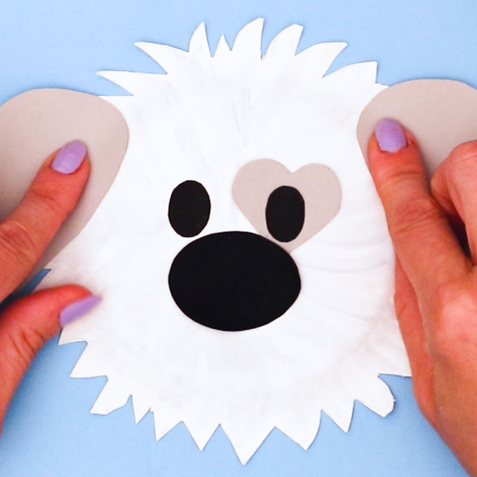 Image of a hand glueing the eyes onto the paper plate.
