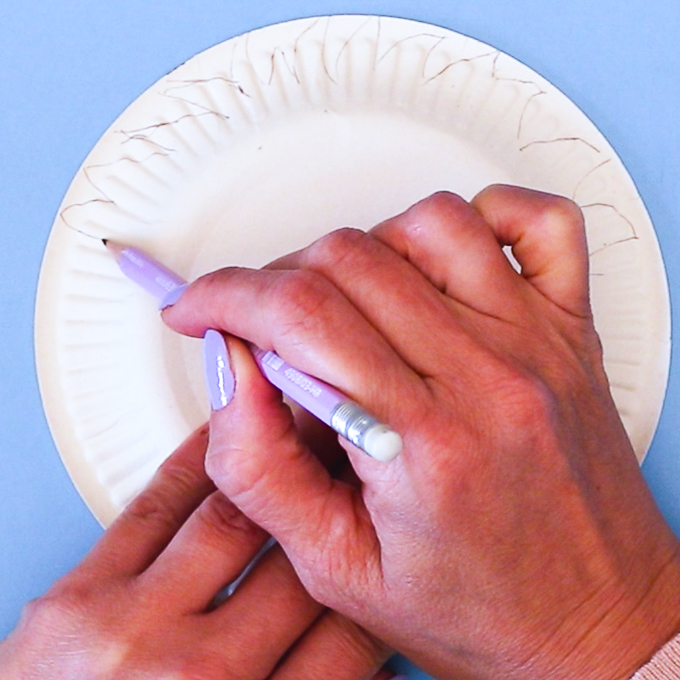 Image featuring a hand drawing a zig-zag shape around the paper plate.