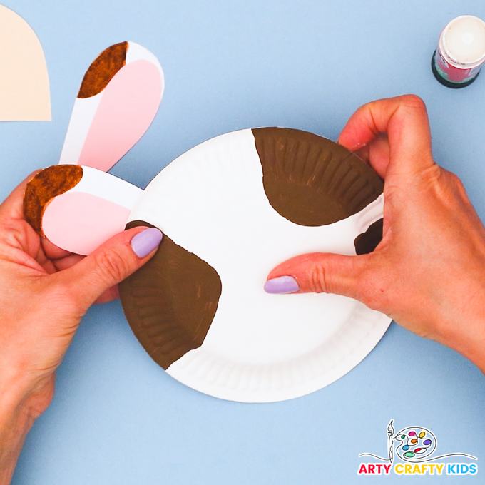 A hand affixing an ear onto the paper plate.