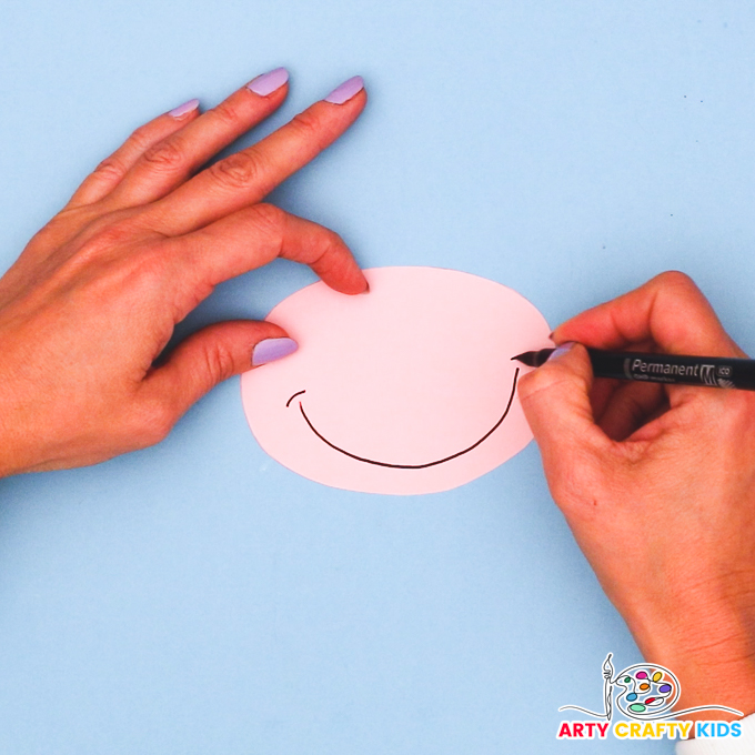 A hand drawing a big smiley face onto  a pink mouth piece.