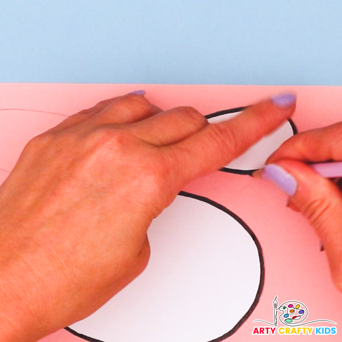 A hand drawing around the cow template pieces onto pink paper.