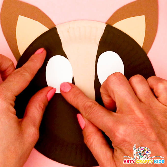 Image of a hand gluing the horse's eyes onto the paper plate.