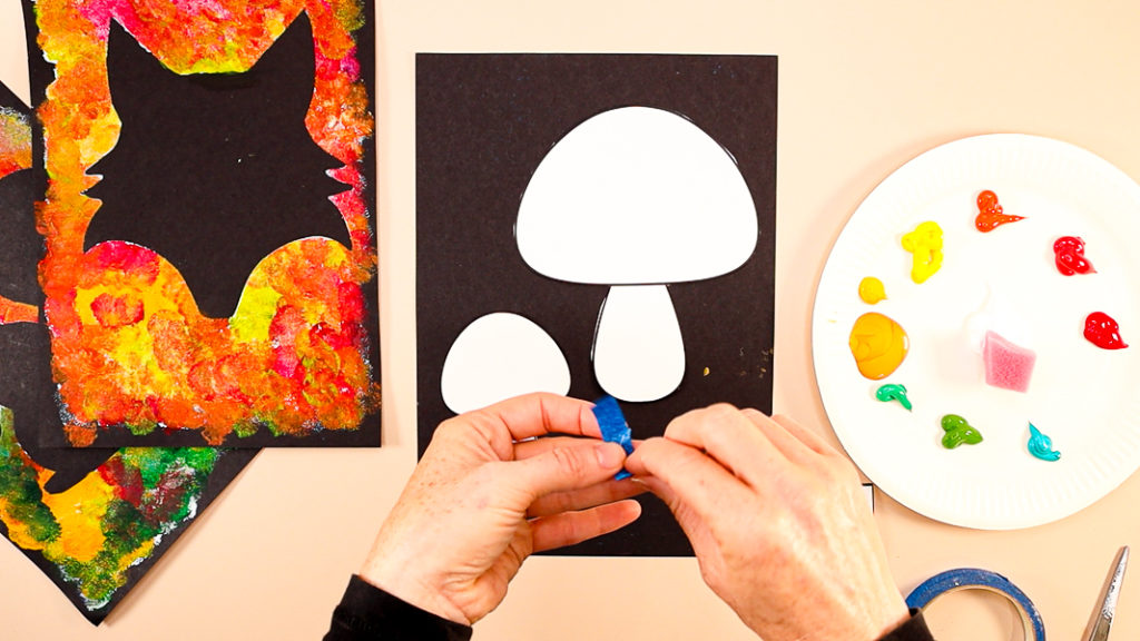 Image of a hand folding over tape to secure the mushrooms to the backing card.