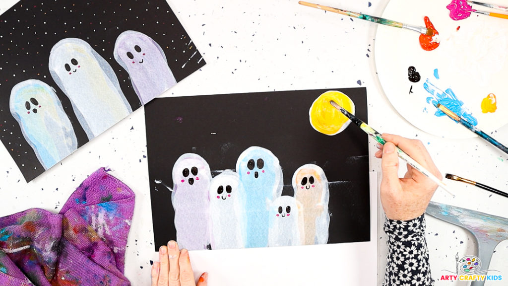 Image of a hand layering the white moon with bright yellow paint.