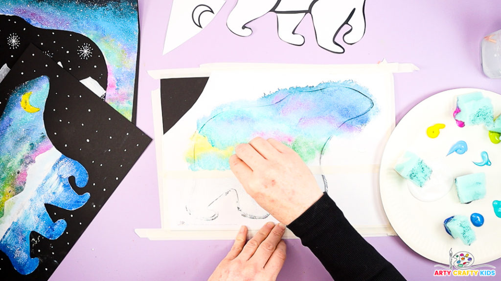 Image of a hand adding yellow, green and pink to the lower sky area within the polar bear.