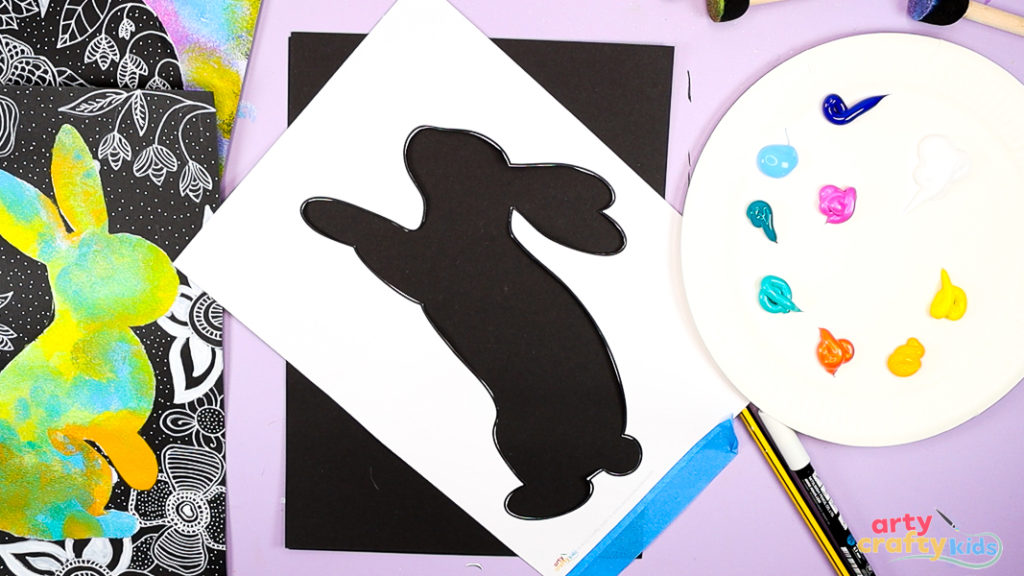 Image of a bunny cut out to create a stencil and placed against a black piece of card stock.