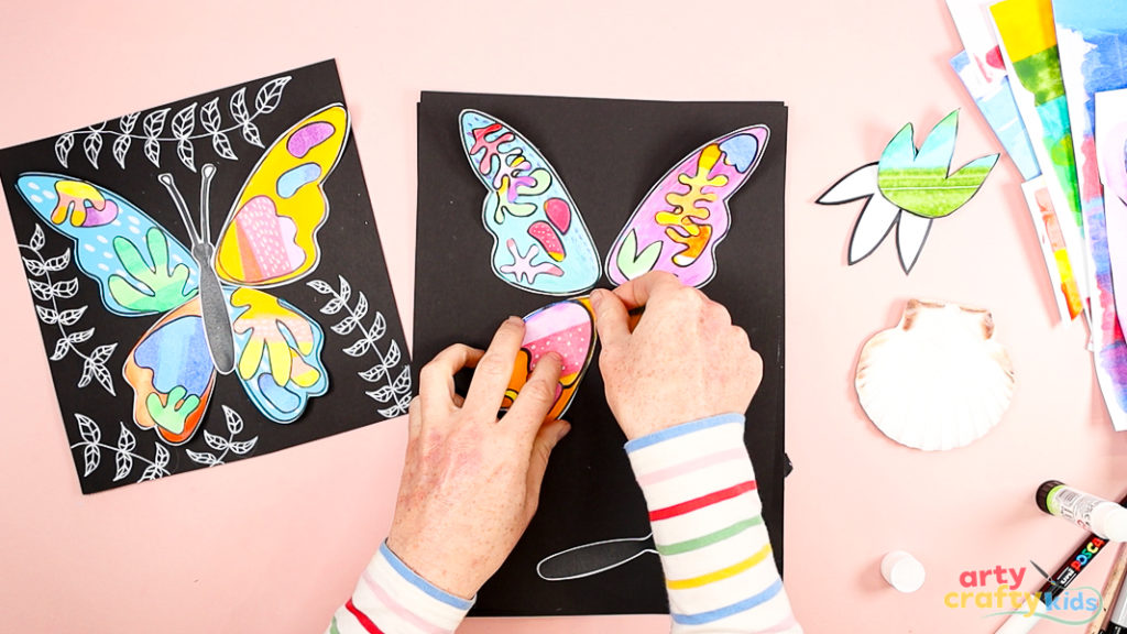 Image of a hand glueing the collaged wings onto the backing card.