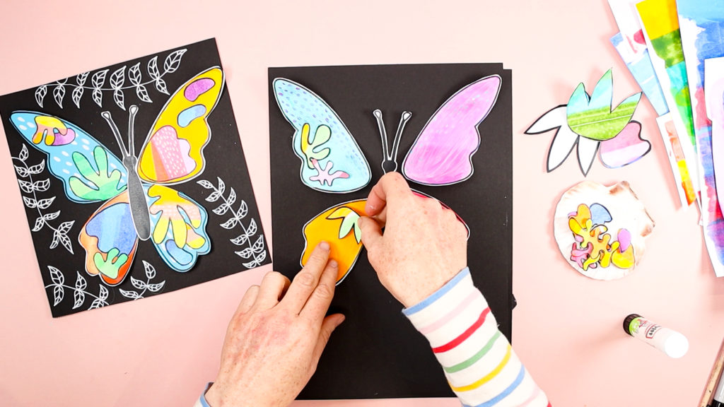 Image of a hand layering the Matisse shapes onto the butterfly wings.