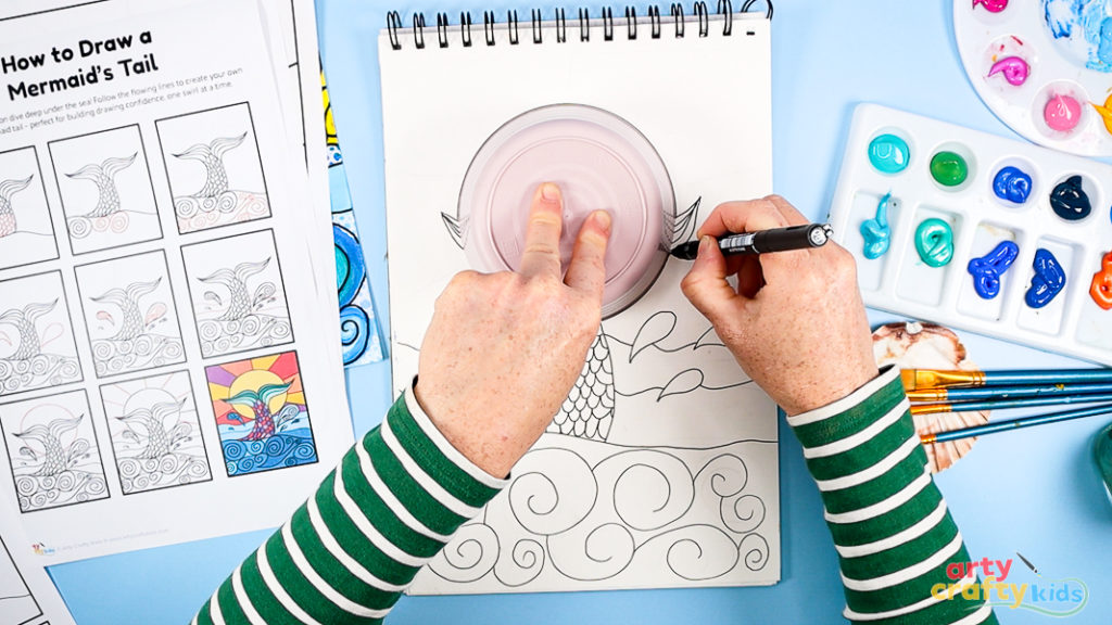 Image of Step 5: Drawing a large sun behind the mermaid tail using a circular shape and dividing the background into sections for pattern and color.