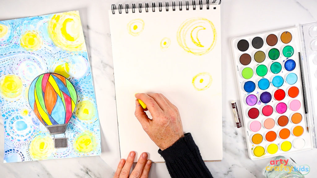 Image of a hand drawing round stars on the white paper.