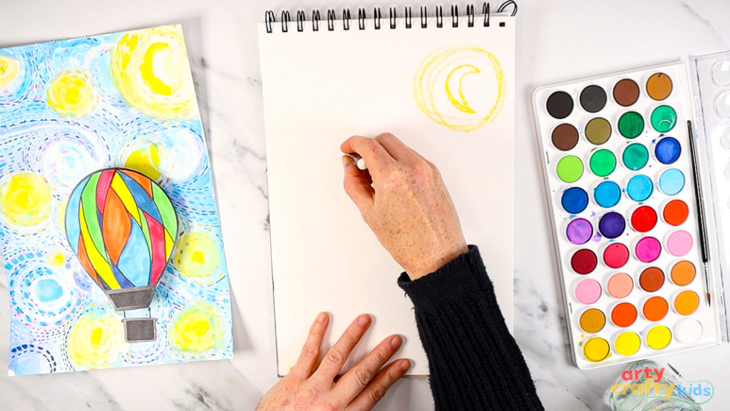 Image of a hand using a white oil pastel to draw dynamic swirls across the page.