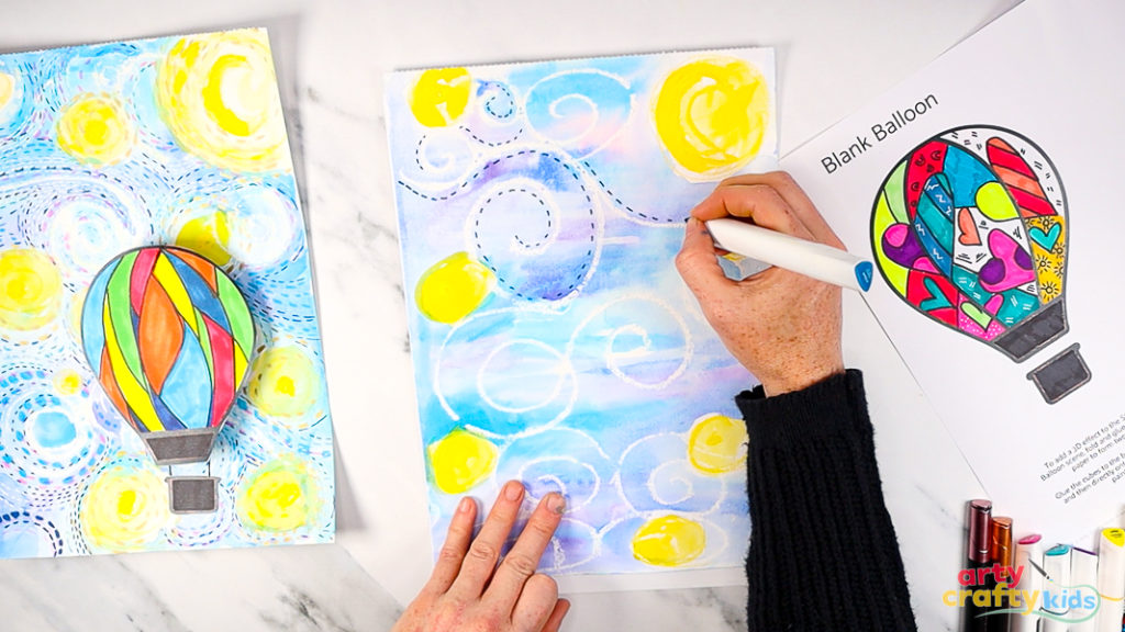 Image of a hand using a blue marker pen to draw a collection of dashed lines around the white wax swirls - adding movement to the Starry Night sky.