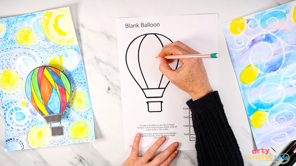 Imahe of a hand drawing a design in pencil onto a blank balloon template.