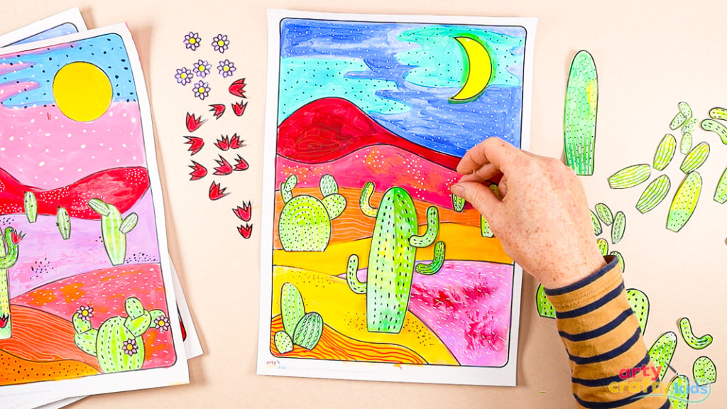 Image of a hand assembling the cactus elements onto the desert landscape.