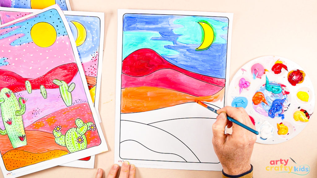 Child painting a colorful desert landscape template using bright acrylic paints, with completed examples and a paint palette nearby