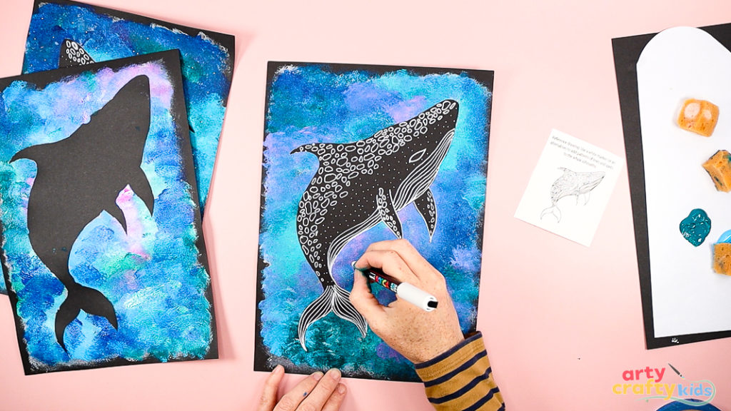 Image of a hand drawing the details of a Whale Shark with a white marker pen.