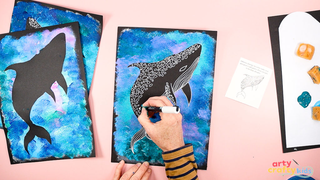 Image of a hand drawing the details of a Whale Shark with a white marker pen.
