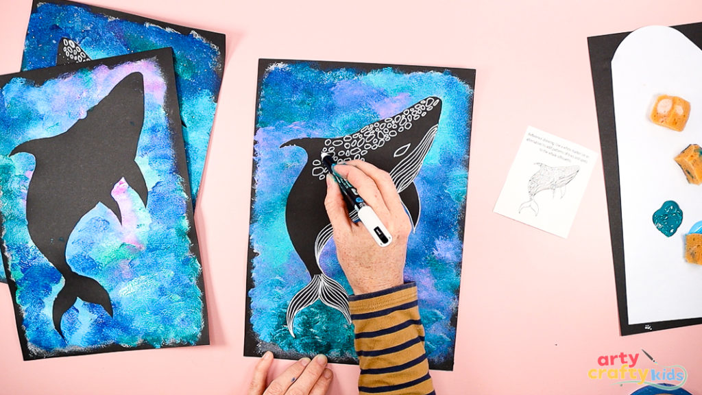 Image of a hand drawing the details of a Whale Shark with a white marker pen.