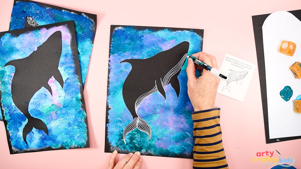 Image of a hand drawing the details of a Whale Shark with a white marker pen.