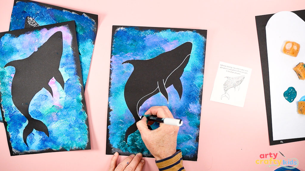 Image of a hand drawing the details of a Whale Shark with a white marker pen.