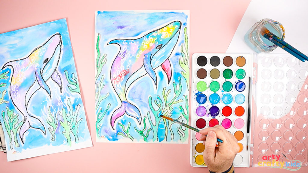 Colorful whale shark watercolor artwork with white crayon detailing and overlapping sea plants drawn in black crayon.