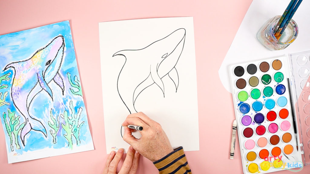 Image of a hand outlining the whale shark template with a black crayon.
