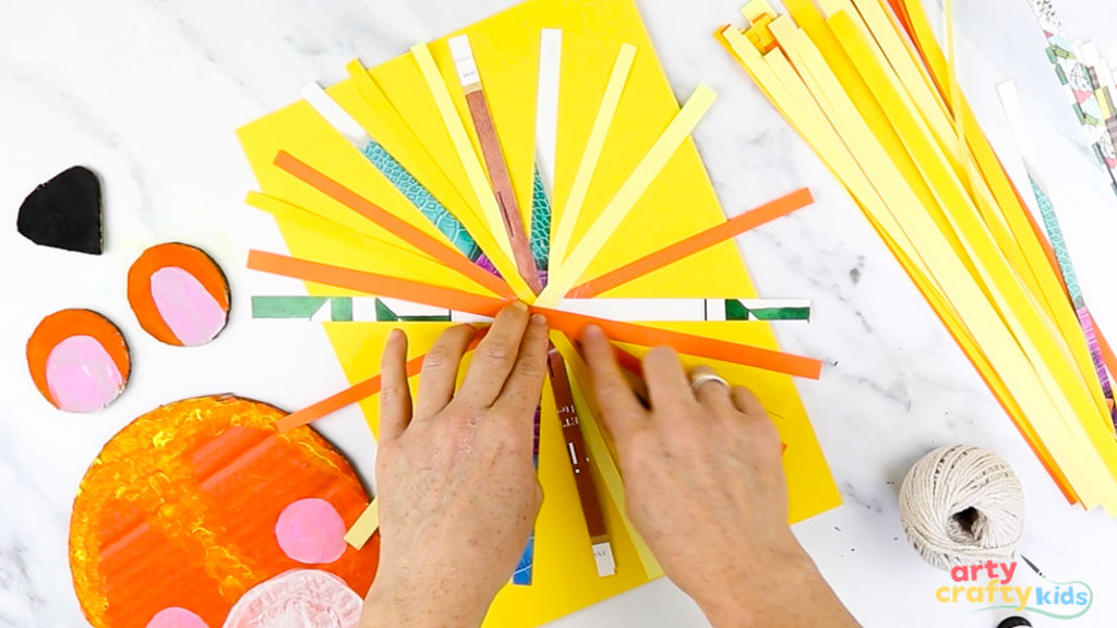 Image of a hand laying strips of paper in a circular pattern.