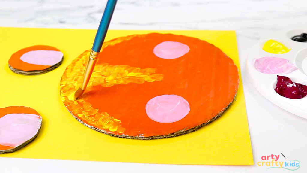 Hand painting yellow markings onto the lions head, with added pink cheeks.