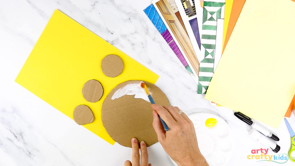 Hand-painting circular cardboard circles - the head, ears, and nose - white.
