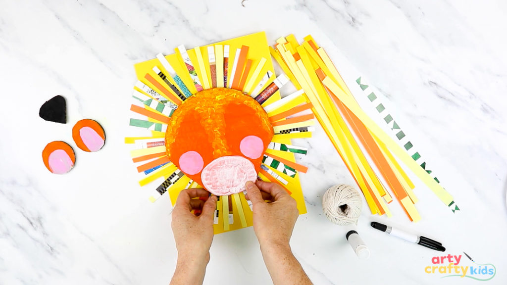 Image of a hand gluing the head onto paper strips.