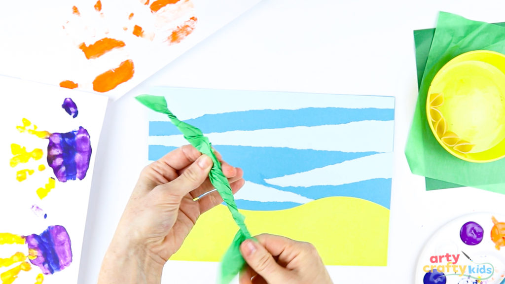 Image of a hand twisting a sheet of green tissue paper to create seaweed.