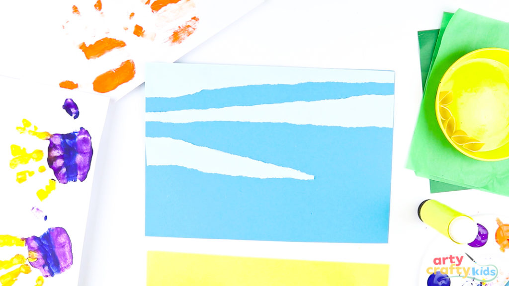 Image of a blue sheet of cardstock with light blue, torn paper strips stuck on top to add texture to the under the sea scene.