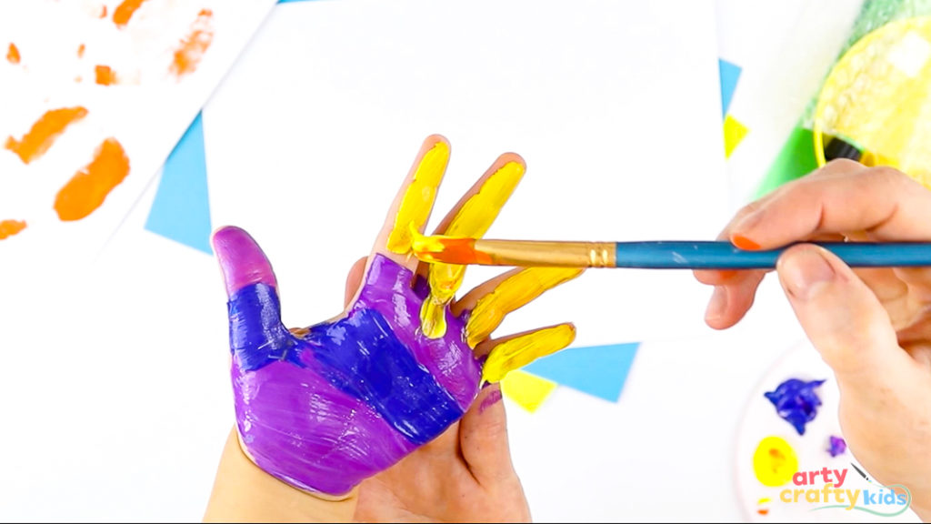 Image of a hand painted in purple and blue stripes with yellow fingers.