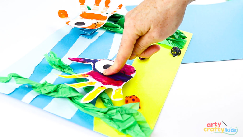 Image of a hand gluing the fish handprint art onto the spring.