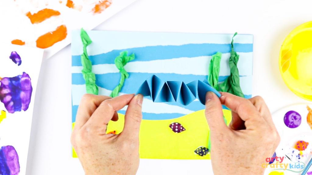 Image of a hand stretching a completed paper spring.
