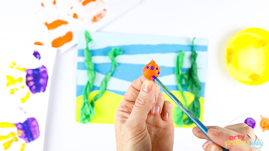 Image of a hand painting a pasta shell.
