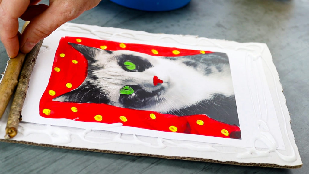 Image showing a hand affixing sticks around the photo of the cat.